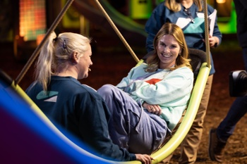 Ariel Mansholt looks at the camera as she sits in inclusive Flexx Swing with Jill Moore