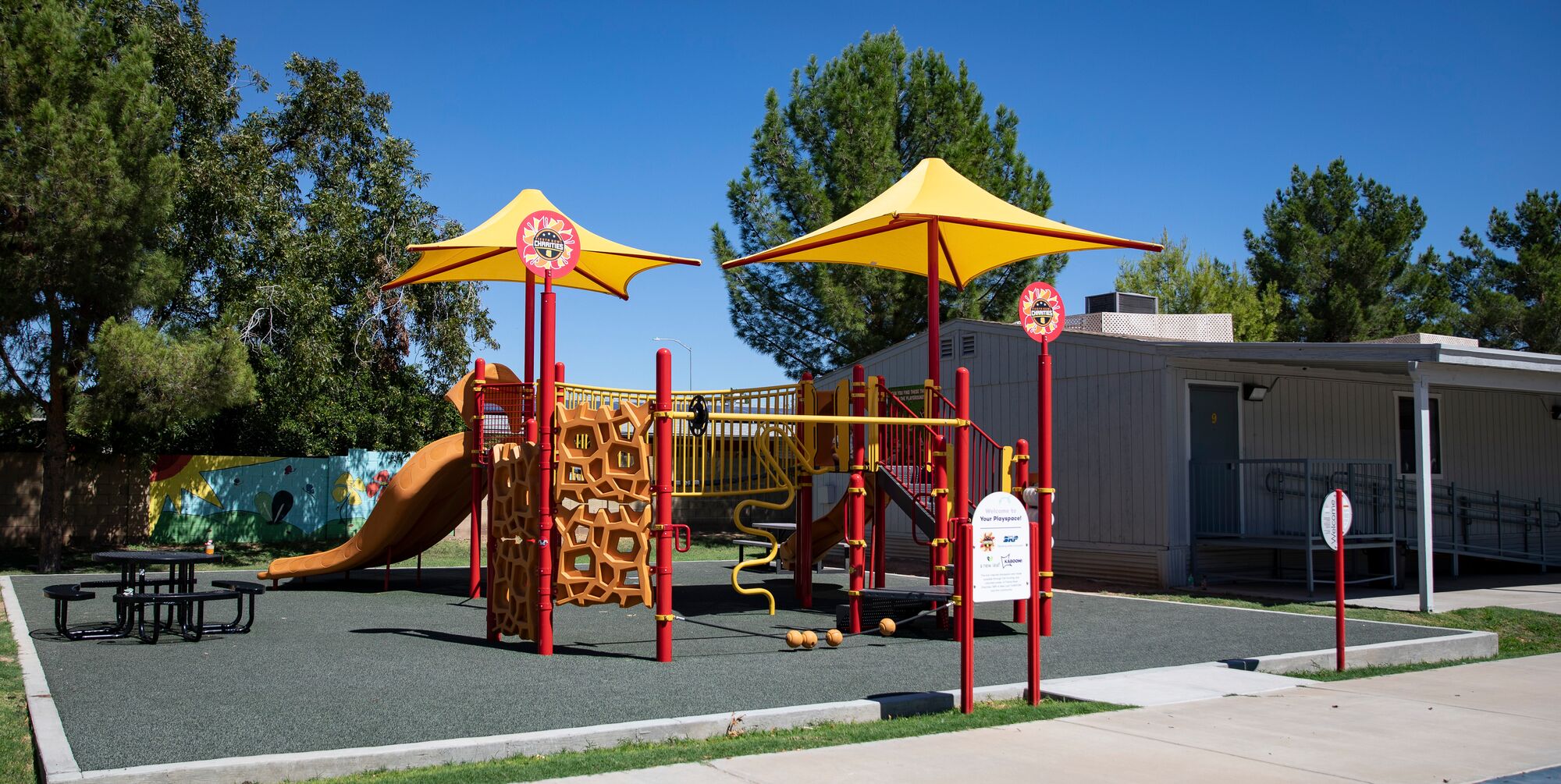 Wide shot of a red, orange and yellow KABOOM! playground 
