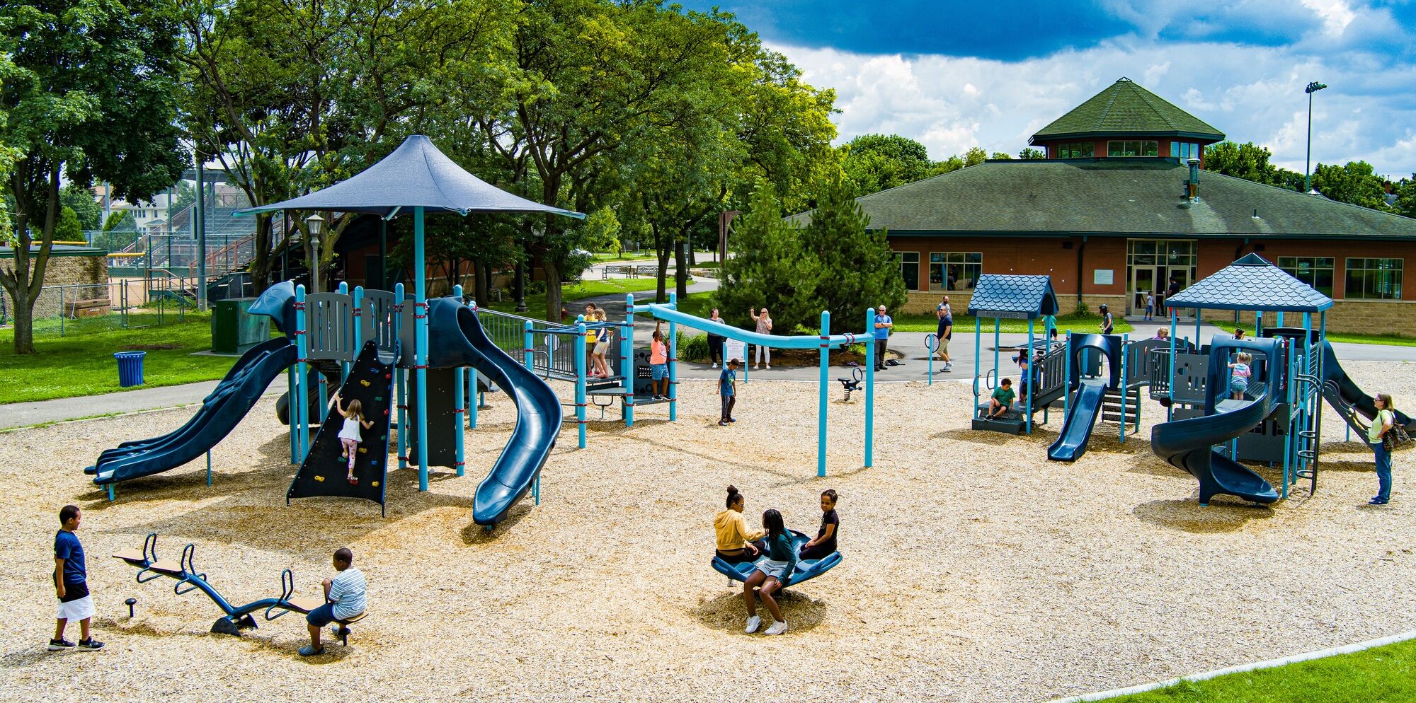Wide shot of a dark-blue colored playground on wood-chipped surfacing