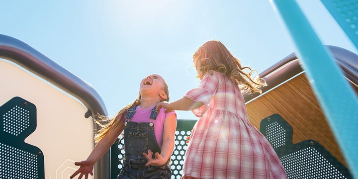 Two children laughing on top of a Hedra geometric play structure 