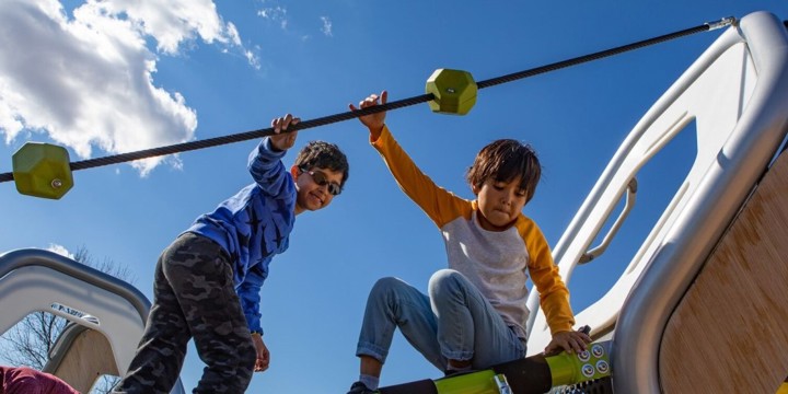 Camera looks up at two boys playing on a Hedra geometric playstructure. 
