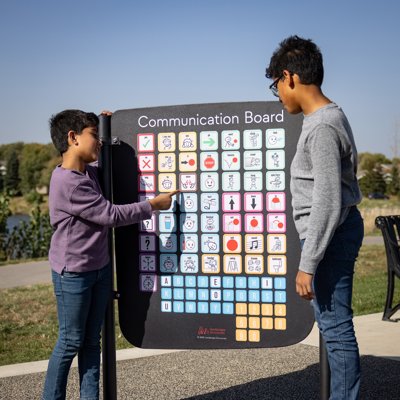 Two boys looking at a Communication Board on a playground